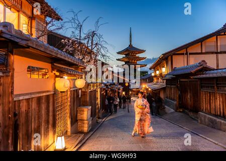 Woman in kimono in a lane, Yasaka dori historical alleyway in the old town with traditional Japanese houses, behind five-storey Yasaka pagoda of the