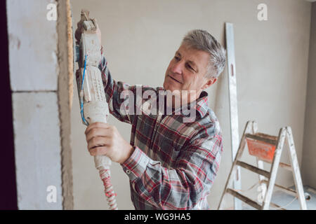 Plasterer smoothing interior wall with machine Stock Photo