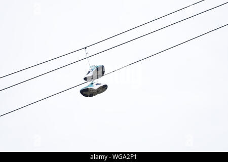 Trainers hanging on overhead cable power line Stock Photo