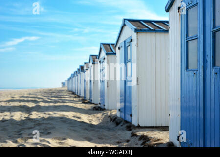 beach huts on the beach of island Texel in the Netherlands with blue sky on sunny summer day, selective focus with focus on right hut and copy space