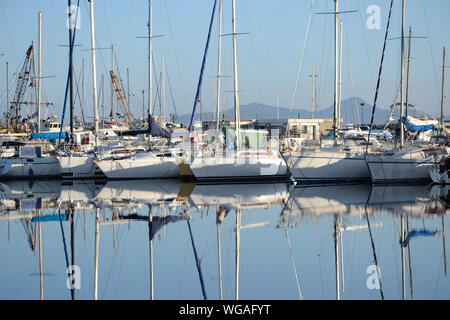 sailboats anchored in the port of Alghero and their reflections on the water Stock Photo