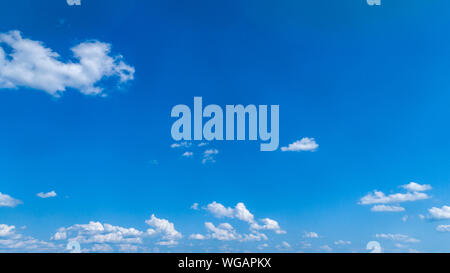 White Fluffy Clouds Floating in the Bright Blue Skies on a Summer Day Stock Photo
