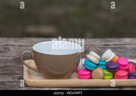 Cup of coffee and Colorful Macaroons in dish on wooden table in garden Stock Photo