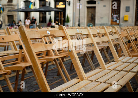 Set of empty folding wood chairs with numbers set on a public square at concert with Nobody attending show Stock Photo
