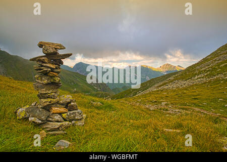 Stone pile marking the path in the mountains at sunset Stock Photo