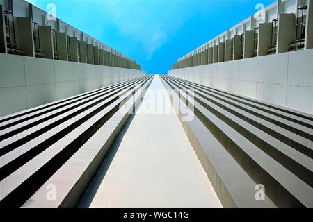 Perspective view up exterior of modern apartment building in Singapore with strong leading lines and architectural detail against blue sky