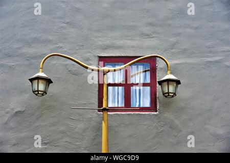 Vintage street lamp and brown framed window on textured grey wall of Singapore house in historic Chinatown, Singapore in close up Stock Photo