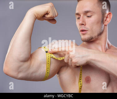 Muscular Man Measuring Bicep With Tape Measure Isolated On A White  Background Stock Photo, Picture and Royalty Free Image. Image 13101726.