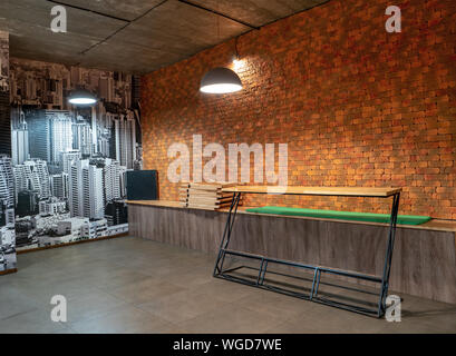 Dark room with brick wall, light and empty table Stock Photo