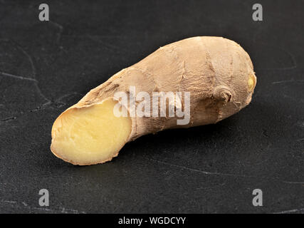 Fresh ginger root piece on dark concrete background Stock Photo