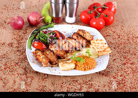 Roasted chicken wings served on a white plate with peppers onions tomatoes Stock Photo