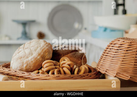 Assortment of breads near a wicker basket on a table in a rustic kitchen. Composition in kitchen at the photo studio Stock Photo