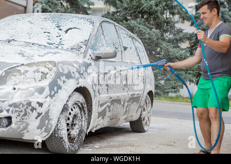 A man washes his car in a self-service sink in the summer outdoors Stock Photo