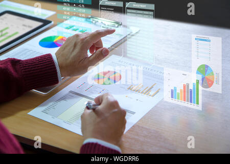 Businessman interacts with virtual reality graphics while deeply reviewing a financial report for a return on investment or investment risk analysis. Stock Photo