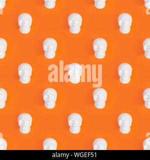 White human skull toy on orange Halloween background with free space for text top view. Stock Photo