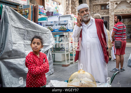 Doha, Qatar - 25 Nov 2016: A young girl costumer with her porter waiting. Taken in Souq Wakif, Doha Stock Photo