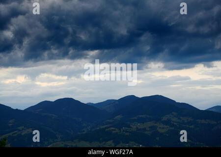 Beautiful summer sunset and landscape - spruces on hills in the evening. Dark sky and silhouette of carpathian mountains. Ukraine. Europe. Travel back Stock Photo