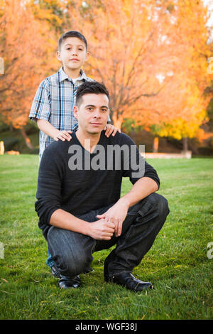 Hispanic Father and Son Portrait Against Fall Colored Trees. Stock Photo