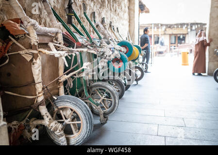 Doha, Qatar - 25 Nov 2016: Row of wheelbarrows waiting for their porter in the early afternoon, with 2 men in the background. Taken in Souq Wakif, Doh Stock Photo