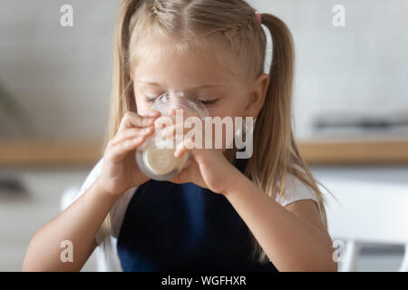 Closeup image little girl holds a glass drinks milk Stock Photo