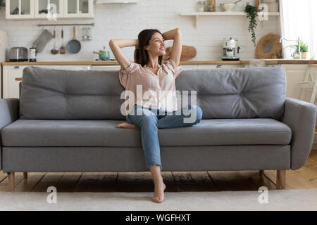In cozy living room happy woman sitting on couch alone Stock Photo