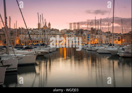 View across the harbour from Vittoriosa to Senglea at dusk with yachts moored. Stock Photo