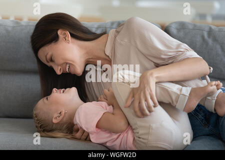 Close up image cheerful mother embraces tickles little daughter Stock Photo