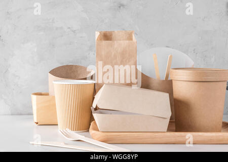 set of eco friendly disposable dishes made of bamboo wood and paper on white marble background. Draped spoons, fork, knives, plate with paper cups. cl Stock Photo