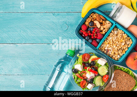 set of lunch boxes with food ready to go for work or school. greek salad, sandwich, vegetables, granola, nuts, berries, eggs and yogurt. meal preparat Stock Photo
