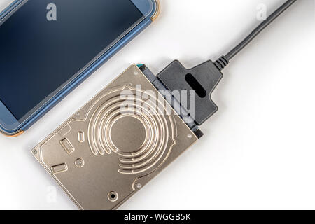 hdd 2.5 hard drive disk connected to smartphone via sata usb cable closeup overhead view Stock Photo