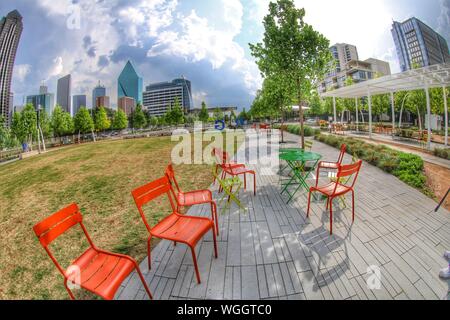 Empty Chairs On Footpath In Garden By Modern Buildings Against Sky