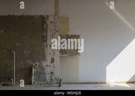 Interior view of old crack damaged white wall. Abandon empty room. Indoor space of renovating construction site. Stock Photo