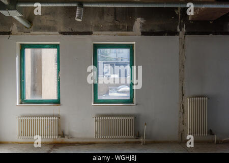 Interior view of empty abandon room with radiator heaters, glass windows and air duct system on ceiling. Stock Photo