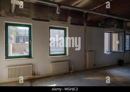 Interior view of empty abandon room with radiator heaters, glass windows and air duct system on ceiling. Stock Photo