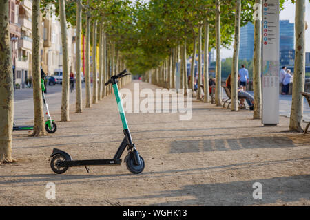 Electric scooters park on promenade riverside of Rhine River in Düsseldorf, Germany with background of diminishing perspective line of trees . Stock Photo