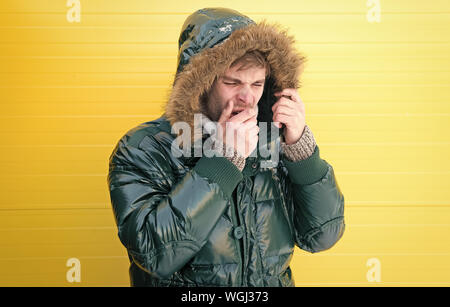Keep warm. Winter stylish menswear. Man bearded hipster wear warm jacket with fur yellow background. Guy wear warm jacket with hood. Feel comfortable in warm clothing. Comfortable winter clothing. Stock Photo