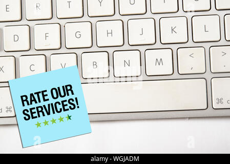 Text of rate our services on notice paper with computer keyboard Stock Photo