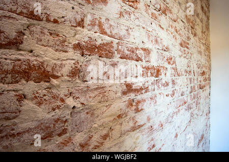 Weathered stained red brick wall background texture peeling plaster Stock Photo