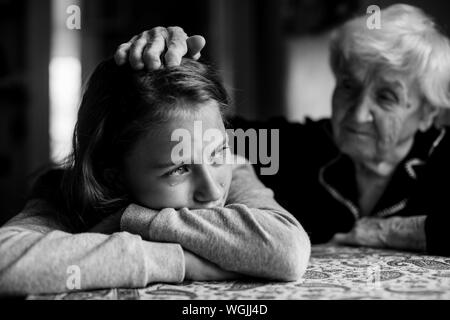 Little girl cries and grandmother soothes and strokes her head. Black and white photo. Stock Photo