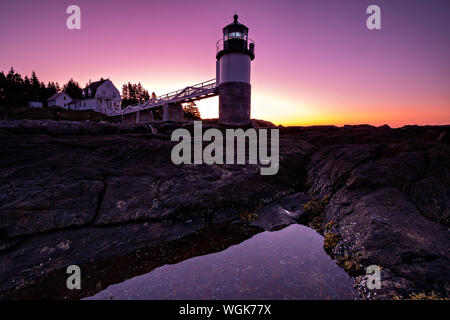 Dawn breaks over the Marshall Point Lighthouse near Port Clyde, Maine. The current lighthouse was built in 1832 on a rocky point of land near the mouth of Port Clyde Harbor and was featured in the major motion picture Forrest Gump. Stock Photo