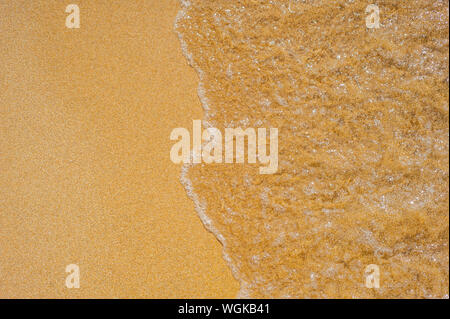 Soft waves with foam of sea on the sandy beach Stock Photo
