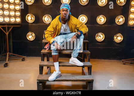 Black rapper in cap sitting on the steps Stock Photo