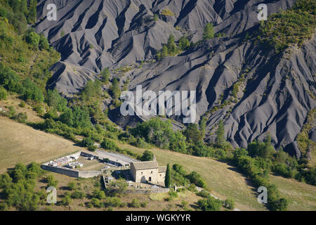 AERIAL VIEW. La Robine-sur-Galabre's 12th century Saint-Pons Chapel with a landscape of badlands (black marl) in the background. France. Stock Photo