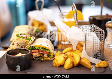 Beef shawarma wrap with vegetables. roasted potatoes and cream sauce on a plate in a caffee or bar Stock Photo