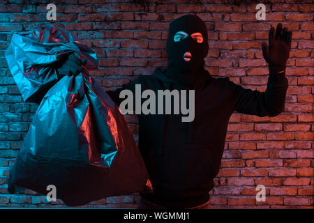 surprised thief hold the hands up and get illuminated from the police lights Stock Photo