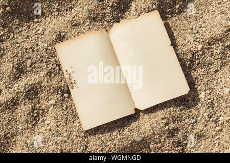 top view of open old and empty pages laying on sand Stock Photo