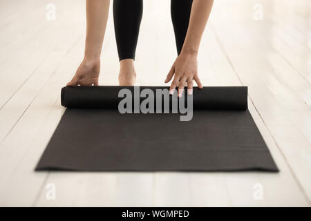 Woman rolling mat before or after practicing yoga close up Stock Photo