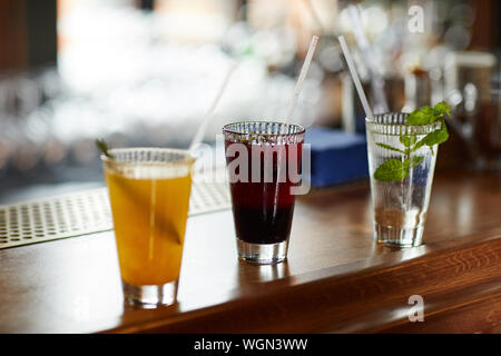 Row of three colorful drinks on bar stand, refreshing cocktails and mojito glass, copy space Stock Photo