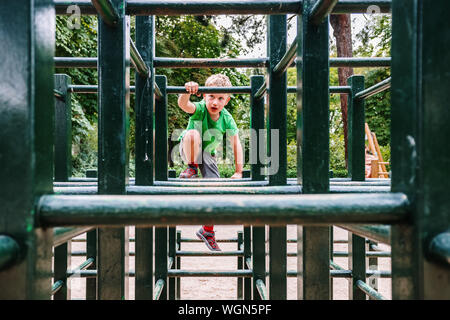 Boy playing in a maze of wooden bars in a park. Stock Photo