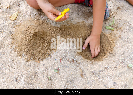 Child hands playing in the sand of a park in summer getting dirty. Stock Photo